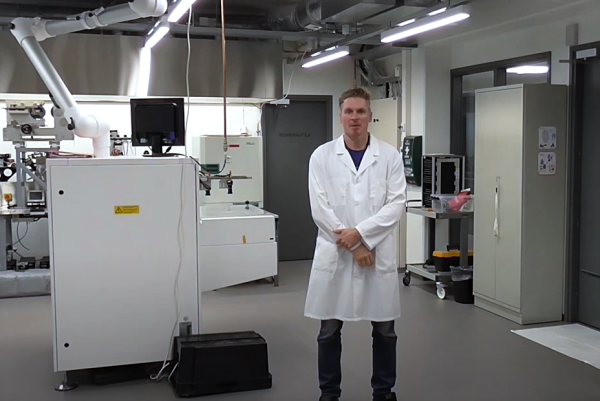 Valokuvassa mies valkoisessa takissa seisoo laboratoriossa.