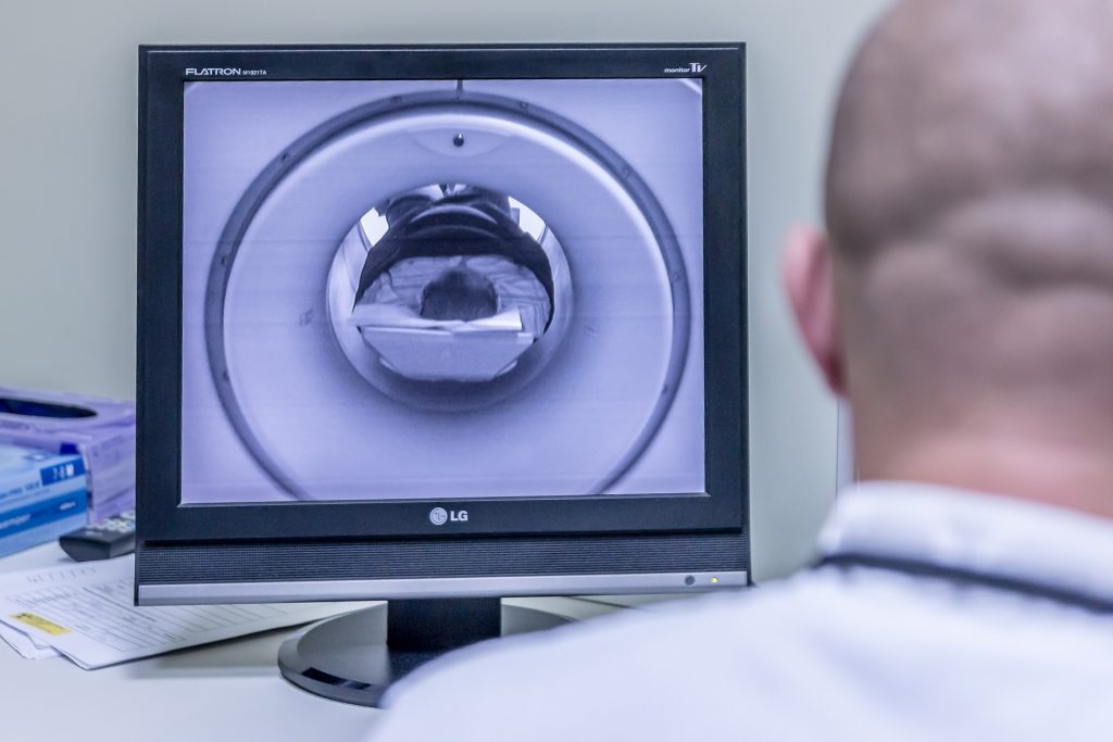 Valokuvassa röntgenhoitaja katsoo tietokoneen ruudulta magneettikuvausta.