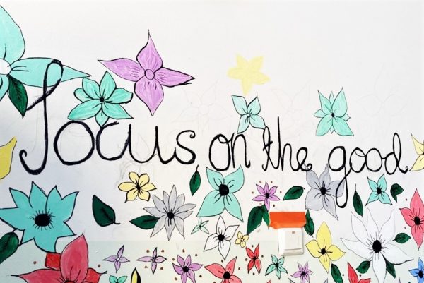 Valokuvassa piirrettyjä kukkia ja teksti "Focus on the good".
