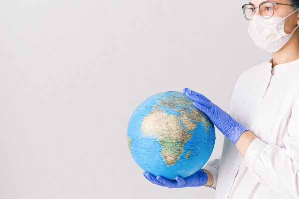 Valokuvassa sairaanhoitaja, jolla on kädessään maapallo.