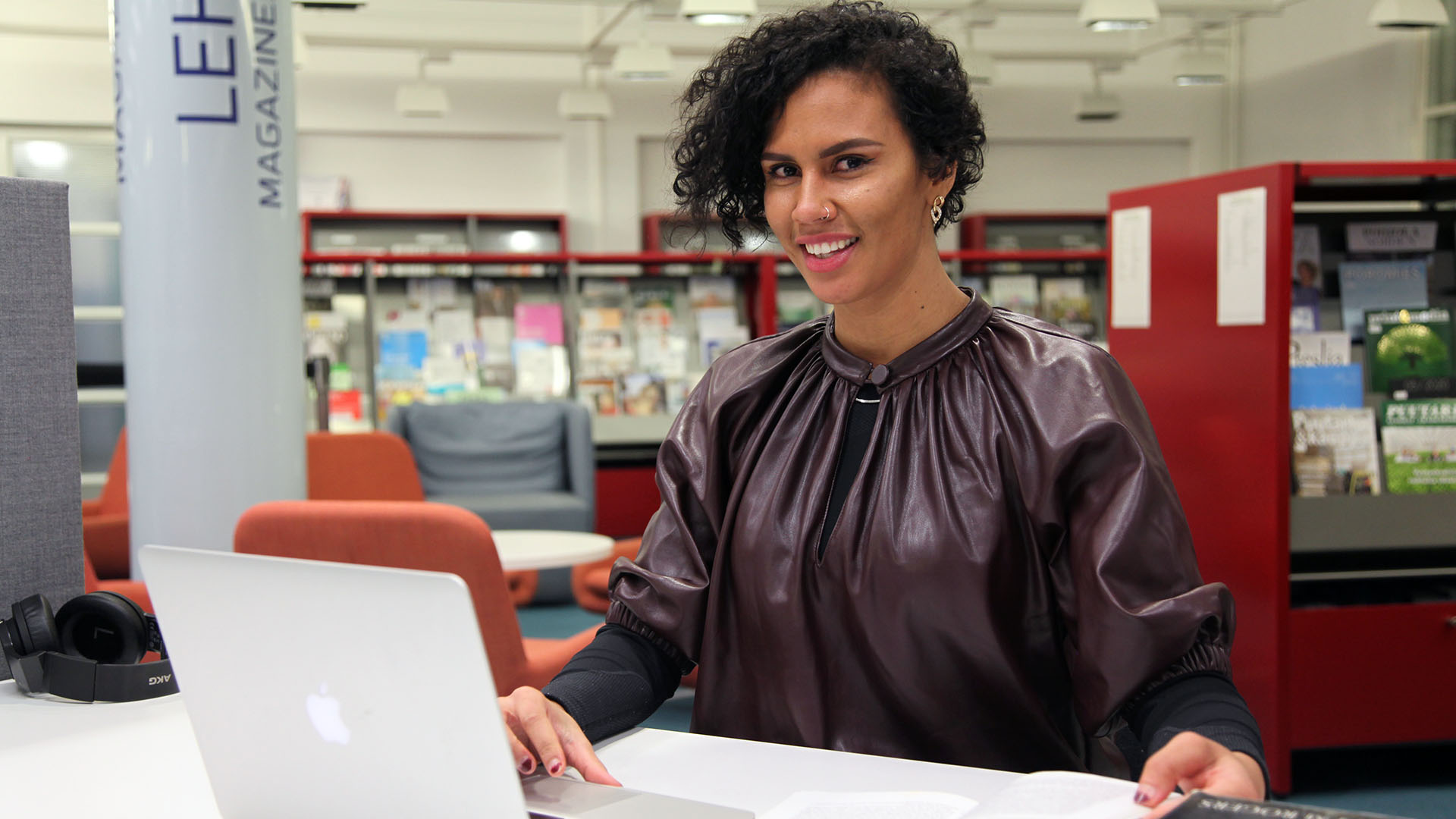 A woman is sitting at a desk with a laptop and books.