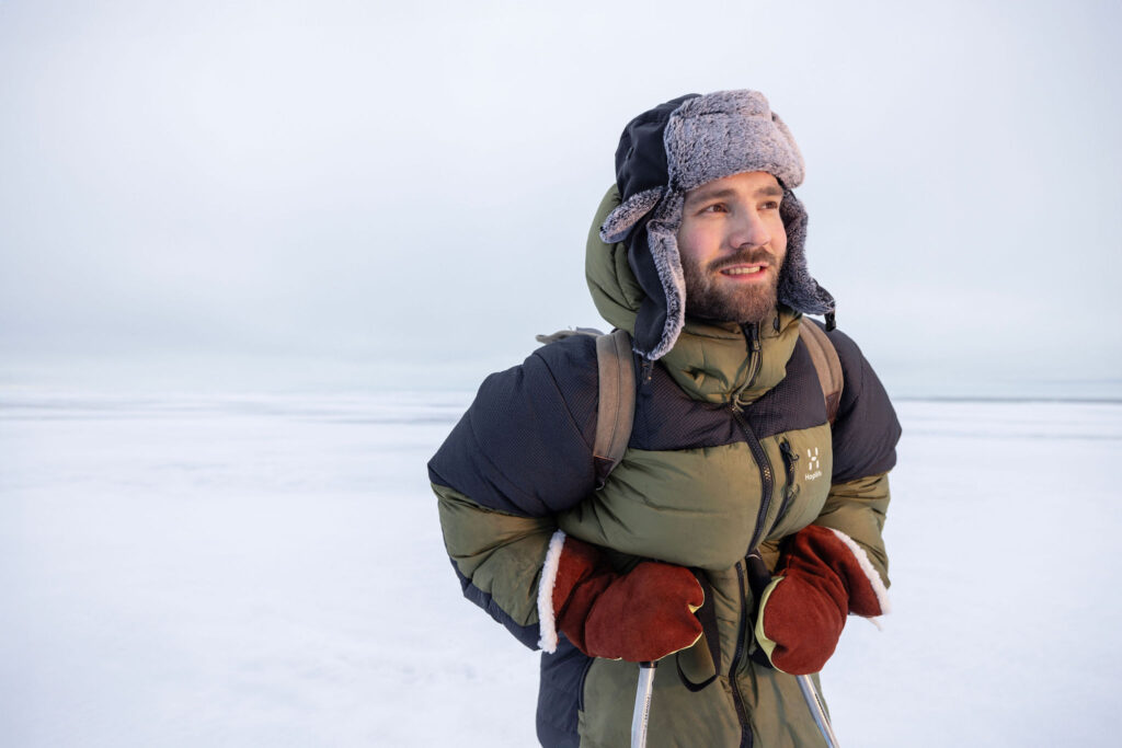 Talvisiin retkivaatteisiin pukeutunut mies järven jäällä katsoo kaukaisuuteen.