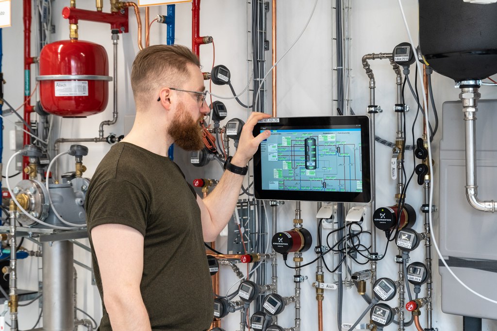 parrakas, silmälasipäinen mies tarkastelee energiaverkon tietoja näytöltä Oamkin hybridilaboratoriossa