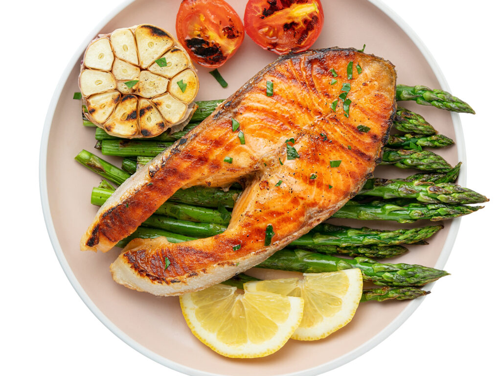 Plate of grilled trout steak and asparagus with ingredients isolated on white background. Top view